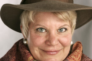 Woman wearing a hat and scarf smiling.